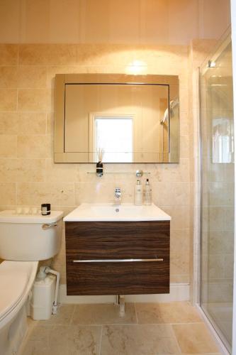 a bathroom with a sink and a toilet and a mirror at Beaufort Lodge - Central Location & Free Parking in Taunton