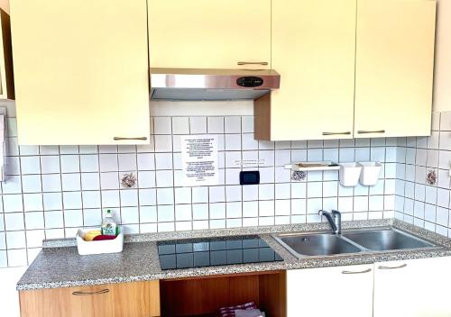 una cocina con paredes de azulejos blancos y fregadero en Gardalakeapartment a Sirmione en Sirmione