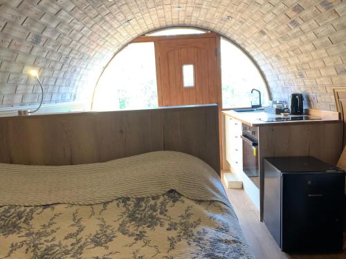 1 dormitorio con 1 cama y cocina con ventana en Romantic escape luxury Hobbit house with Hot tub!, en Sheerness