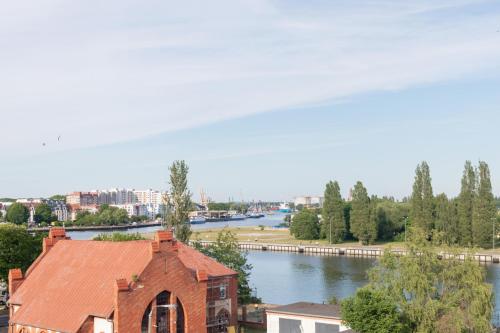 Blick auf einen Fluss und ein Gebäude mit einem Dach in der Unterkunft Riverside Apartments by Renters in Świnoujście