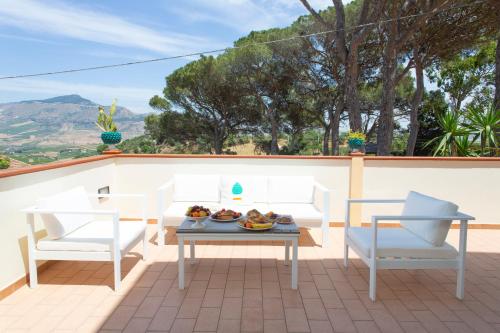 a patio with white chairs and a table with fruit on it at Feudo Giglio Country Charme in Calatafimi