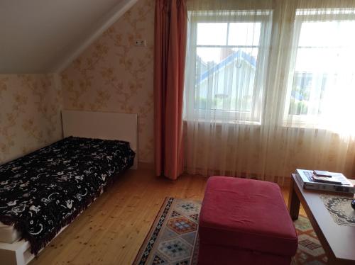 a bedroom with a bed and a table and windows at Apartamentai Tigro guolis Rusnėje in Rusnė