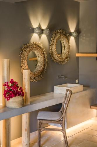 a bathroom with a table and a chair and mirrors at Avithos Resort Hotel in Svoronata