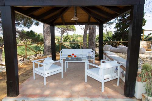 a patio with white chairs and a table and a couch at Feudo Giglio Country Charme in Calatafimi