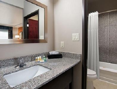 a bathroom with a sink and a toilet and a mirror at Days Inn by Wyndham Dilley in Dilley