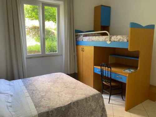 een slaapkamer met een bed, een bureau en een stapelbed bij Là Mì Cà in La Spezia
