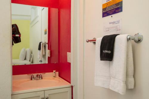 a bathroom with a sink, mirror, towel rack and towel dispenser at Edwardian Hotel in San Francisco