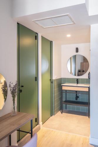 a bathroom with green doors and a sink and a mirror at LATROUPE Grand Place Hostel in Brussels