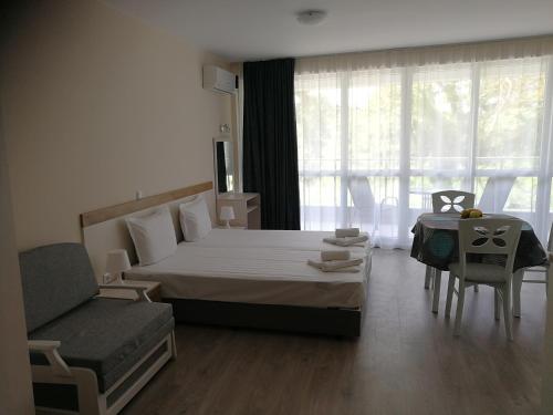 a bedroom with a bed and a chair and a couch at Donchevi Apartments in Primorsko