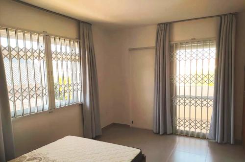 1 dormitorio con 1 cama y 2 ventanas grandes en Casa na praia em SC com Wi-Fi e churrasqueira, en Pinheira