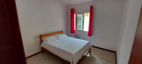 a bedroom with a bed and a window with red curtains at Aldeia St Sebastien 31 Arembepe in Arembepe