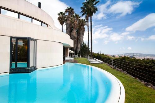 a swimming pool next to a building with palm trees at Villa Rock in Barcelona