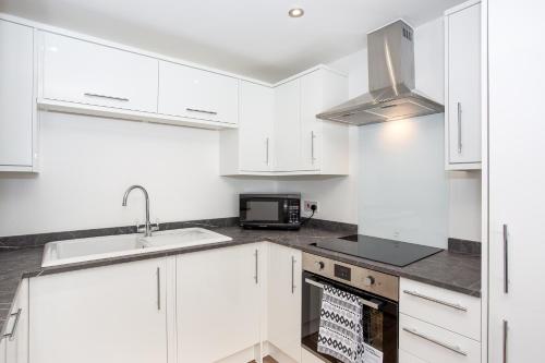 a kitchen with white cabinets and a sink and a microwave at Preston Mews by Sorted Stay - 3 Bed House with a Hot Tub & Free Parking in Southend-on-Sea