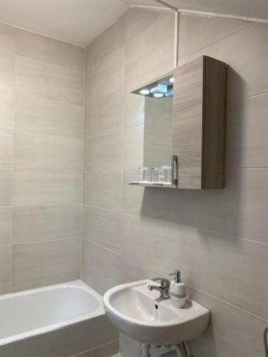a white bathroom with a sink and a bath tub at Kiskakas Étterem in Zalaegerszeg