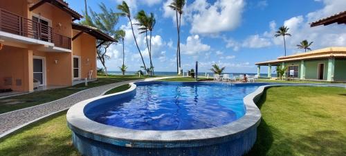 a swimming pool in a yard next to a house at Aldeia St Sebastien 31 Arembepe in Arembepe
