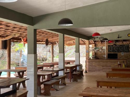 um restaurante com mesas e bancos de madeira e uma cozinha em Pousada Cachoeira Dos Sonhos em Serra Negra