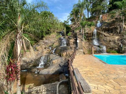 une cascade à côté d'une piscine dans un complexe dans l'établissement Pousada Cachoeira Dos Sonhos, à Serra Negra