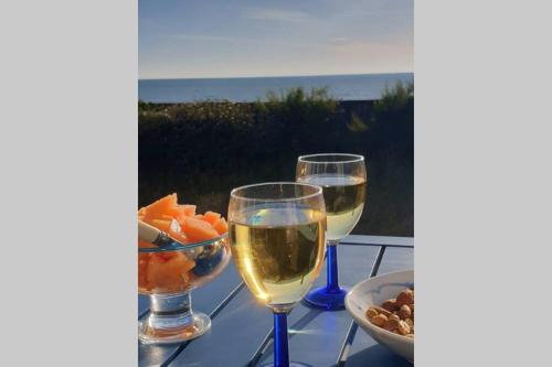 deux verres de vin et un bol de fruits sur une table dans l'établissement Villa La Hautaise vue sur mer, à Hauteville-sur-Mer