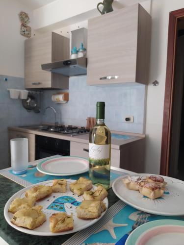 una mesa con dos platos de comida y una botella de vino en Via Marina 19 - Casa sul mare. en Buggerru