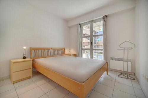 une chambre avec un grand lit et une fenêtre dans l'établissement MODERNE 3 PIECES CANNES CENTRE AVEC BALCON l! A2B67, à Cannes