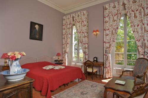 een slaapkamer met een rood bed en 2 ramen bij Château Juvenal in Saint-Hippolyte-le-Graveyron