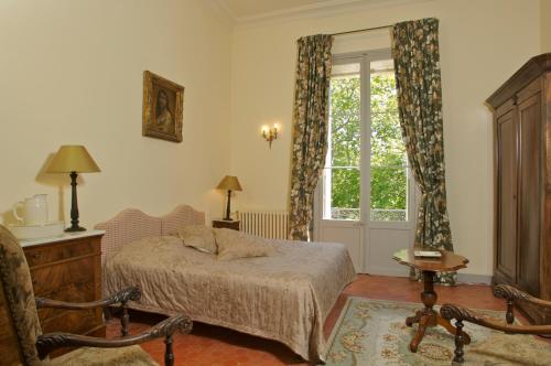 een slaapkamer met een bed en een raam bij Château Juvenal in Saint-Hippolyte-le-Graveyron