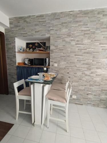 a kitchen with a table and chairs and a stone wall at Via Marina 19 - Casa sul mare. in Buggerru