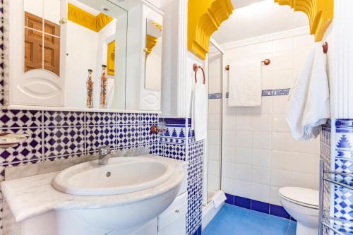 uma casa de banho azul e branca com um lavatório e um WC em Ático El Pasero con Solarium y Barbacoa em Alcaucín