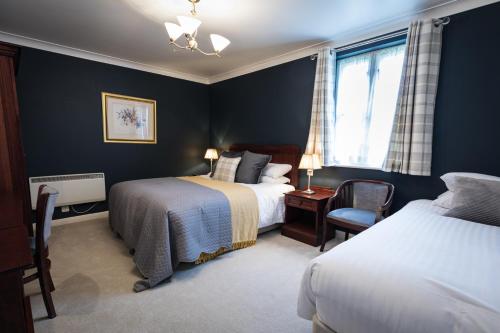 a bedroom with two beds and a chair and a window at Duke Of Marlborough in Woodstock