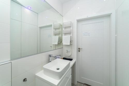a white bathroom with a sink and a mirror at Luxury Yacht z tarasem - Neptun Park by OneApartments in Gdańsk