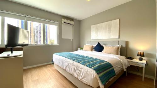 um quarto com uma cama, uma televisão e 2 janelas em QSA - Anora Spaces - Metropolis Alphaville em Barueri
