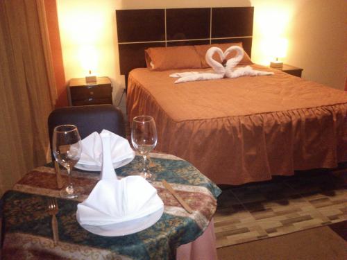 a hotel room with a bed and two tables with glasses and towels at Madison Suite in Tacna
