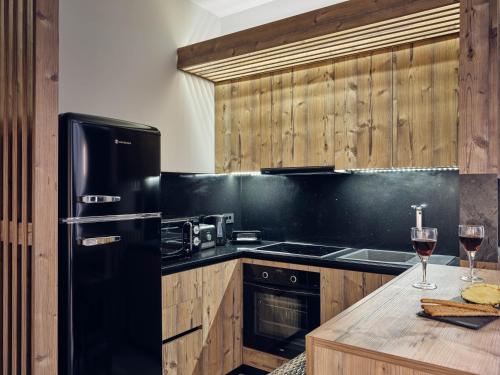 a kitchen with a black refrigerator and two glasses of wine at SAVVAS & JOANNA BOUTIQUE in Laganas