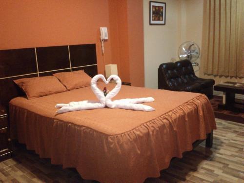 two white swans forming a heart on a bed at Madison Suite in Tacna