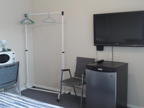 a room with a tv and two chairs and a bed at Apple Tree Inn in Penticton