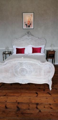 a large white bed with red pillows in a bedroom at Le Derrien in La Roche-Derrien
