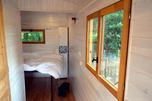 a small bedroom in a tiny house with a window at Roulotte paisible au milieu de la nature in Sainte-Eulalie-en-Born