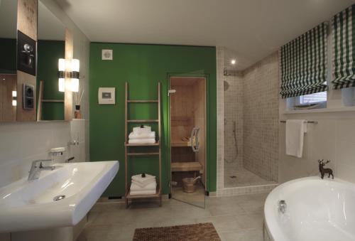 Apartments am alten Rathaus في اوبرستدورف: حمام مع حوض استحمام أبيض وجدار أخضر