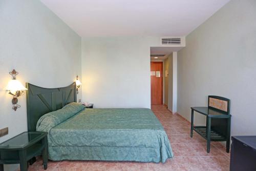 a bedroom with a green bed and a table at KAKTUS Hotel Kaktus Albir in Albir