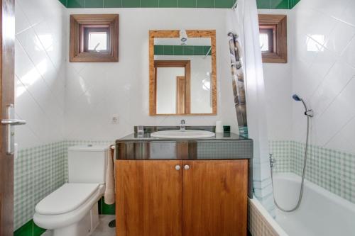 łazienka z umywalką, toaletą i lustrem w obiekcie Villa 1B w mieście Playa Blanca