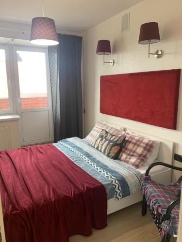 イジェフスクにあるGreen Park Apartmentのベッドルーム1室(赤いヘッドボード付きのベッド1台、窓2つ付)