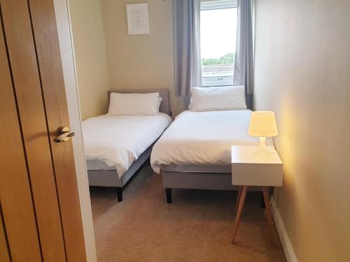 two beds in a small room with a window at 7 Isallt Lodges-3 bed-Ground Floor-Outside seating in Trearddur