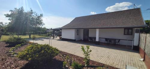 a white house with a roof and a patio at Feszty-fészek Vendégház in Tiszafüred