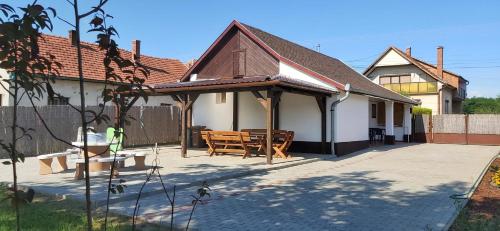 a house with a pavilion with a table and chairs at Feszty-fészek Vendégház in Tiszafüred