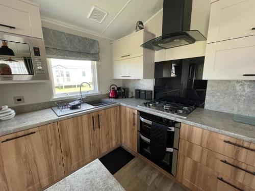 a kitchen with wooden cabinets and a stove top oven at Seton sands holiday park - Premium caravan - 2 bedroom sleeps 4 in Port Seton