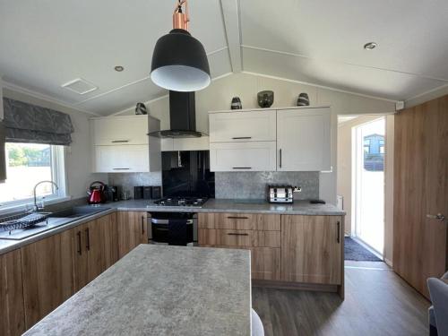 a kitchen with wooden cabinets and a stove top oven at Seton sands holiday park - Premium caravan - 2 bedroom sleeps 4 in Port Seton
