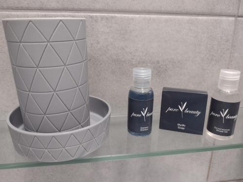a shelf with two bottles of soap and a vase at Hostel Helios in Września