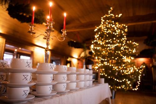 a table with white cups and a christmas tree at Åkerblads Hotell Gästgiveri Spa in Tällberg