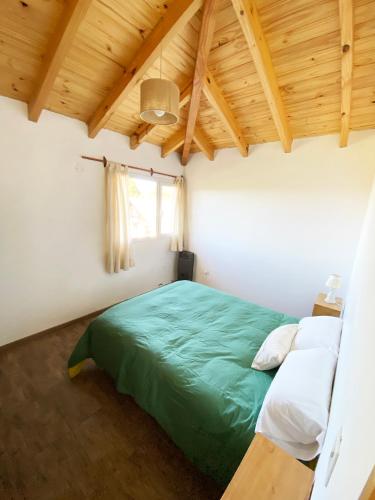 a bedroom with a green bed and white pillows at Hermoso departamento con vista al cerro catedral! in San Carlos de Bariloche