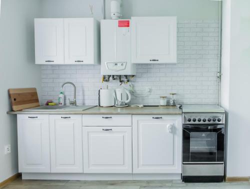 a white kitchen with white cabinets and a stove at Apartament u Basi in Gdańsk
